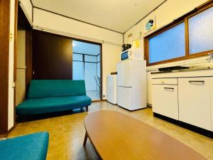 a living room with a chair and a refrigerator at サービスアパ―トメントSAPPORO札幌さくら2-3 in Sapporo