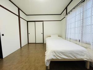 a bedroom with a white bed and a window at サービスアパ―トメントSAPPORO札幌さくら2-3 in Sapporo
