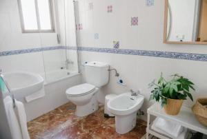a white bathroom with a toilet and a sink at SunShine Mezquita in Córdoba
