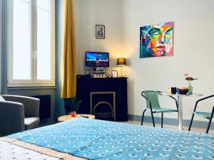 a bedroom with a bed and a table and a tv at Studio Cosy avec Jardin in Roanne