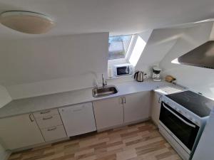 a small white kitchen with a sink and a stove at Ferielejlighed Skovby ved Bogense in Bogense +4 photos