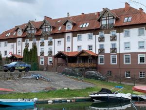 a large building with boats in the water in front of it at Apartamenty Żeglarskie w Vęgorii in Węgorzewo