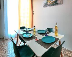 a white table with green chairs and wine bottles on it at Alexandra's Apartment in Volos