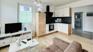 a kitchen and living room with a couch and a tv at Kajüte Jonas in Thiessow