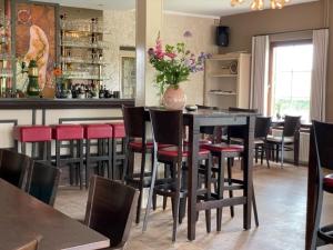 a restaurant with a bar with red chairs and a table at Hotel Kreutzer in Heijenrath