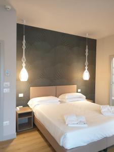 una camera da letto con un grande letto bianco con due pendant light di Hotel De La Ville depandance di Hotel Augustus a Fano