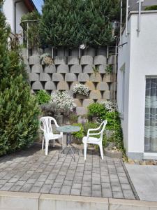 a patio with two chairs and a table in front of a wall at Ferienwohnung Elvira in Dätzingen