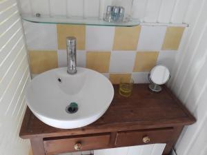 - un lavabo blanc sur une table en bois avec un miroir dans l'établissement Peniche Caroline, à Capestang