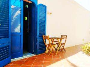 dos sillas y una mesa frente a una puerta azul en Il Villaggio Eoliano, en Santa Marina Salina