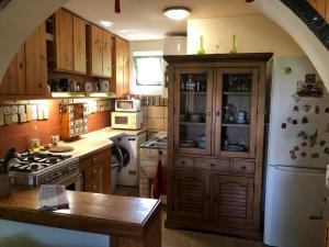 cocina con armarios de madera y nevera blanca en Szendergő - Apartman Hajós pincefalu, en Hajós