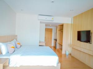a bedroom with a white bed and a flat screen tv at HATCHAO HERITAGE BEACH FRONT RESORT in Ban Hat Cha Samran
