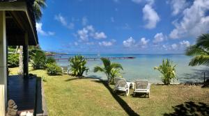 deux chaises assises sur l'herbe près de l'océan dans l'établissement Poerani Moorea, à Moorea