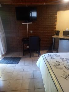 a room with a bed and a desk and a television at Kgatholoha Guest House in Klerksdorp