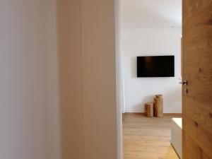 Habitación con TV en una pared blanca en Huber - Das Tiroler B&B en Oberperfuss