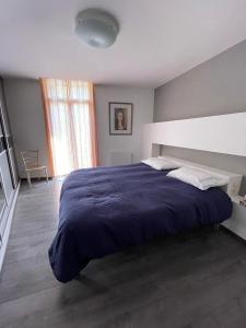 een slaapkamer met een groot bed en een blauwe deken bij Le Kerrete in Céret