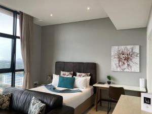 a bedroom with a bed with a couch and a desk at Urban Awe Apartment- iTowers 18th Floor in Gaborone