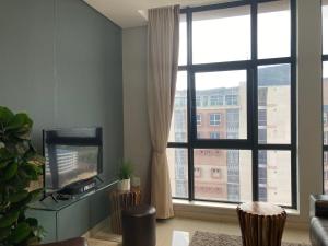 a living room with a television and a large window at Urban Awe Apartment- iTowers 18th Floor in Gaborone