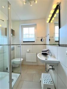 W łazience znajduje się toaleta z prysznicem i umywalka. w obiekcie Ferienwohnung 7, OG, Hof zur Sonnenseite Fehmarn w mieście Fehmarn