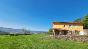 ein gelbes Haus mit einer Steinmauer auf einem Feld in der Unterkunft Agriturismo La Corte in Pistoia