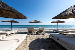 una playa con sillas y sombrillas y el océano en NewStory Luxury Suites Possidi, en Possidi