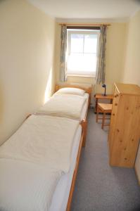 two beds in a room with a desk and a window at Ferienwohnung 7, OG, Hof zur Sonnenseite Fehmarn in Fehmarn