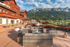 a resort patio with couches and tables and a mountain at MONDI Appartements am Grundlsee in Grundlsee