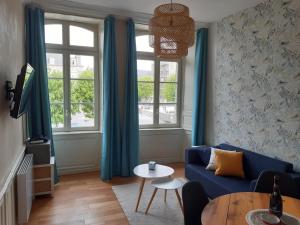 uma sala de estar com um sofá azul e uma mesa em L'Aparthé Dinan - Vue sur la place du marché em Dinan
