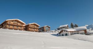 un groupe de bâtiments sur une pente enneigée dans l'établissement Kar Design Appartements, à Lech am Arlberg
