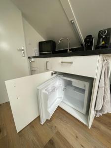 a small white kitchen with a sink and a refrigerator at Boetje 51 in Den Burg