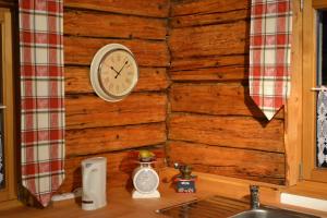 a kitchen counter with a clock on a wooden wall at Ferienhaus Ederhof - Idyllischer Vierseithof, kinder- und hundefreundlich, Referenzen auf FeWo-direkt nachlesbar in Aidenbach +18 photos
