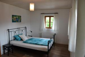 a bedroom with a bed with blue sheets and a window at Ferienhaus Ederhof - Idyllischer Vierseithof, kinder- und hundefreundlich, Referenzen auf FeWo-direkt nachlesbar in Aidenbach