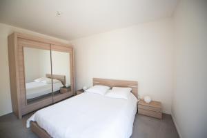 a bedroom with a large white bed and a mirror at Appartements de 2 ou 3 chambres à 40 minutes de Paris in Evry-Courcouronnes