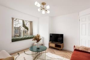 ein Wohnzimmer mit einem Sofa und einem TV in der Unterkunft Luxe Design - Chic Cottage - Heart of Rothbury in Rothbury