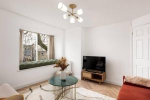 a living room with a couch and a television at Luxe Design - Chic Cottage - Heart of Rothbury in Rothbury