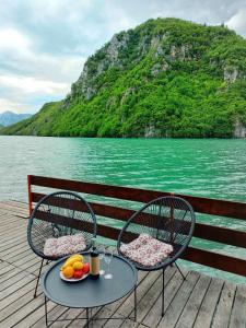 two chairs and a table with a plate of fruit on a dock at Raft Perućac in Rastište