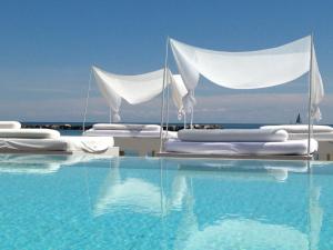 a swimming pool with white beds and the water at Vistamare Suite in Lido di Savio