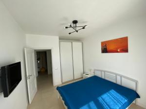 a bedroom with a blue bed and a flat screen tv at Apartament Park View Campus in Constanţa