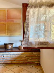 ventana con cortina sobre una mesa de madera en Gubbio-Gualdo Tadino Incantevole mansarda con terrazza, en Gualdo Tadino