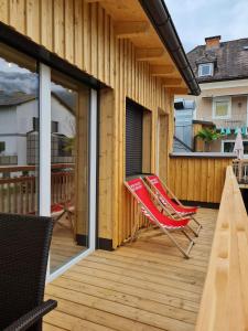 a deck with a red rocking chair on a house at Santa Lucia Apartments in Bodensdorf