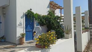 un edificio blanco con una puerta azul y flores en Enjoy Cyclades studios & suites en Kíthnos