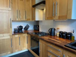 een keuken met houten kasten en een fornuis met oven bij Spacious 2-bed flat with garden, 3 minutes walk from Oval tube station in Londen