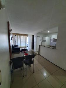 Una sala de estar con mesa y sillas y una cocina. en Praia Mansa Suíte Hotel, en Fortaleza