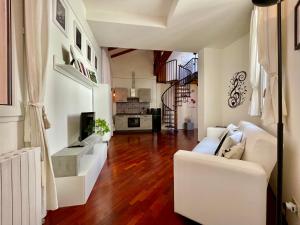 a living room with a white couch and wooden floors at LA CHIAVE DI VIOLINO Appartamentino musicale in Bologna