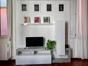 sala de estar con TV en una pared blanca en LA CHIAVE DI VIOLINO Appartamentino musicale, en Bolonia