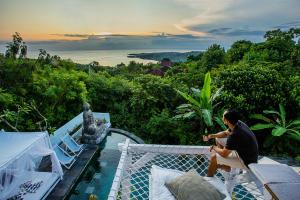 a man sitting on the ledge of a villa at The Puncak Private Villa in Nusa Lembongan