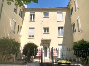 un bâtiment avec une clôture devant lui dans l'établissement Magnifique appartement T2 aux portes de Paris, à Cachan