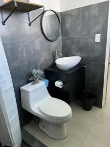 a bathroom with a white toilet and a sink at Nomada Beach Hostel- Isla Verde in San Juan