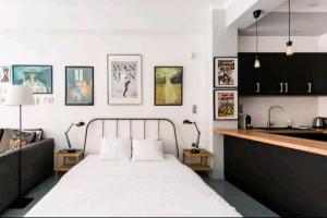 a bedroom with a white bed and a kitchen at Explore a New Arts District from a Hip Studio Flat in Athens