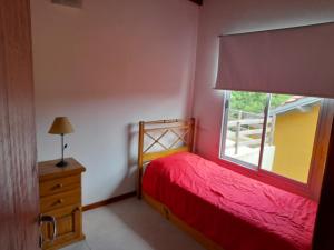 a bedroom with a red bed and a window at Barra's Del Sur. in Mar del Plata