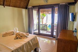 a room with a bed with a table and a balcony at Krisna Bungalows and Restaurant in Sekotong